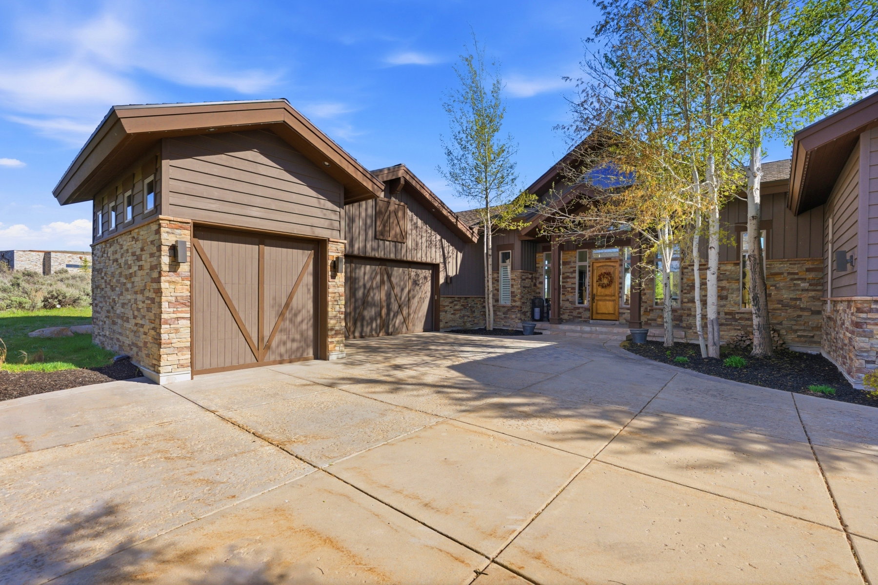 Exterior featuring stone facade, wood siding, and multiple garage doors