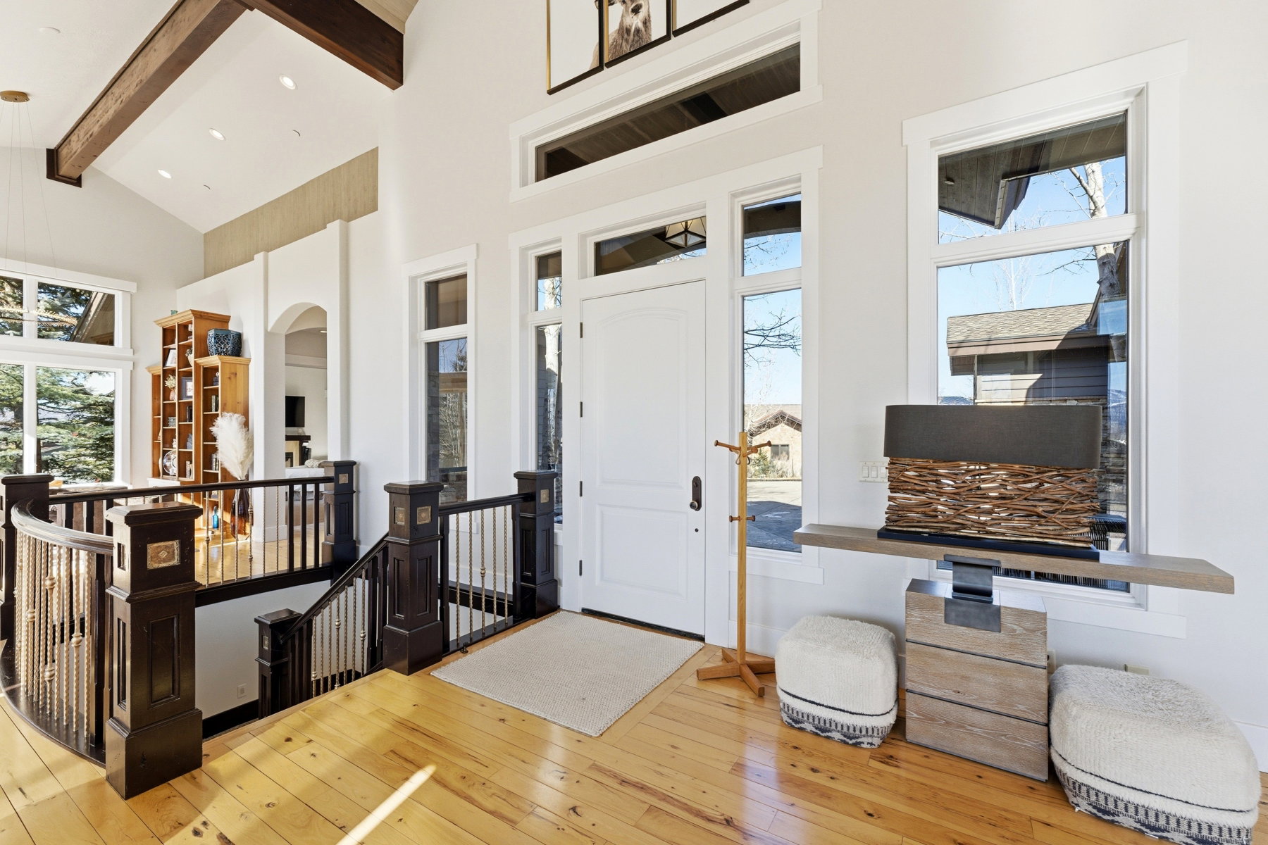 Entryway featuring a white paneled door, light wood-finish flooring, and a dark wood staircase