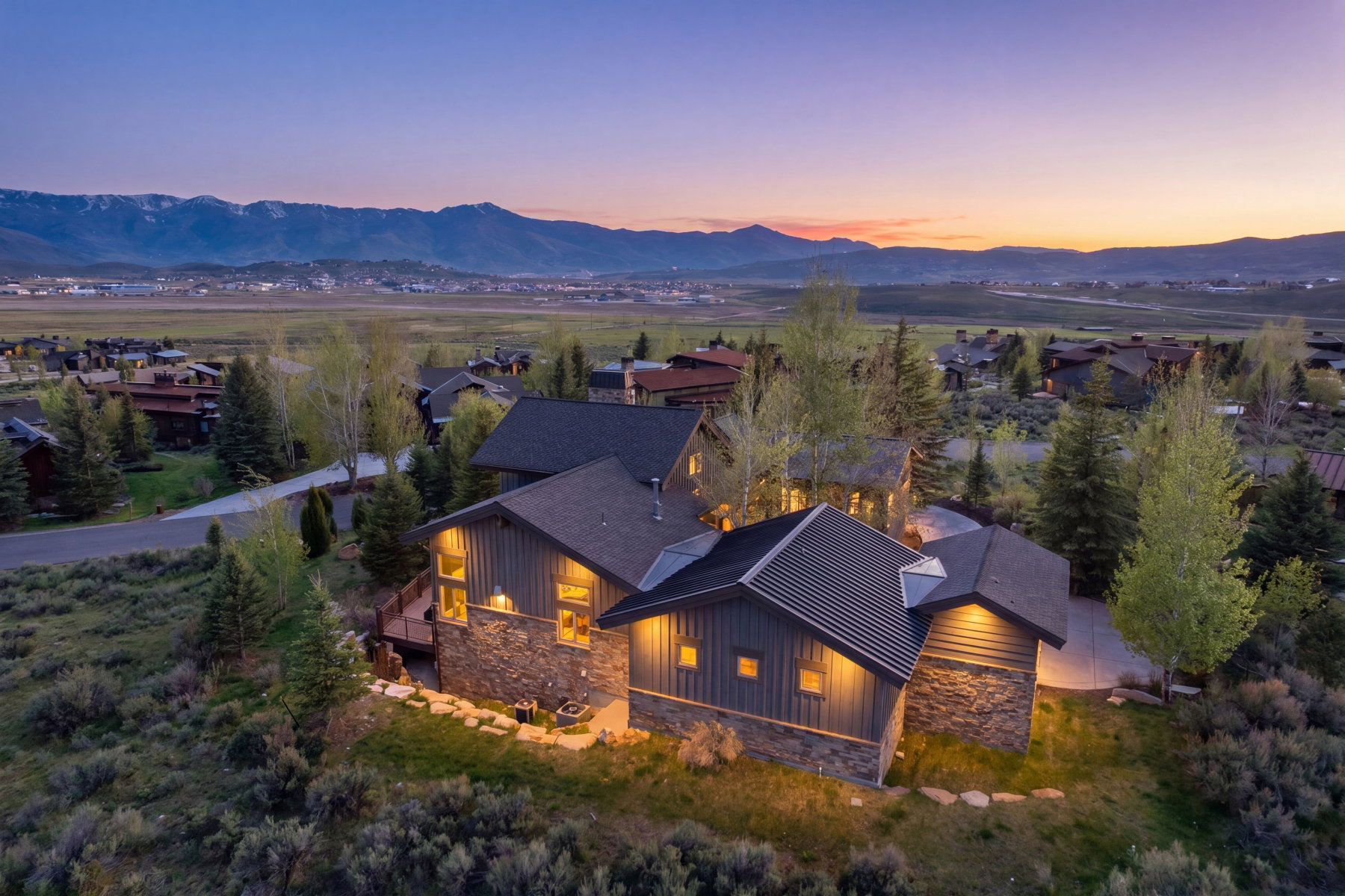 Mountain contemporary residence featuring stone and horizontal siding, multiple gabled roofs, and a prominent deck