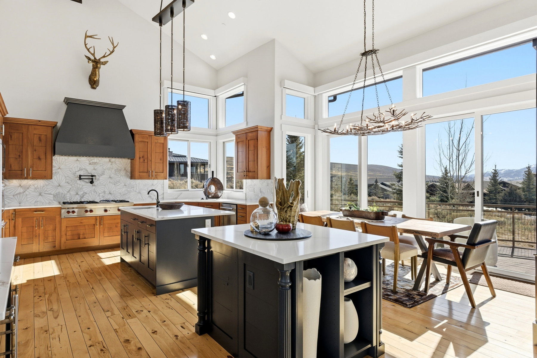 Open-concept kitchen and dining area featuring natural wood-finish flooring, a vaulted ceiling, and extensive window walls