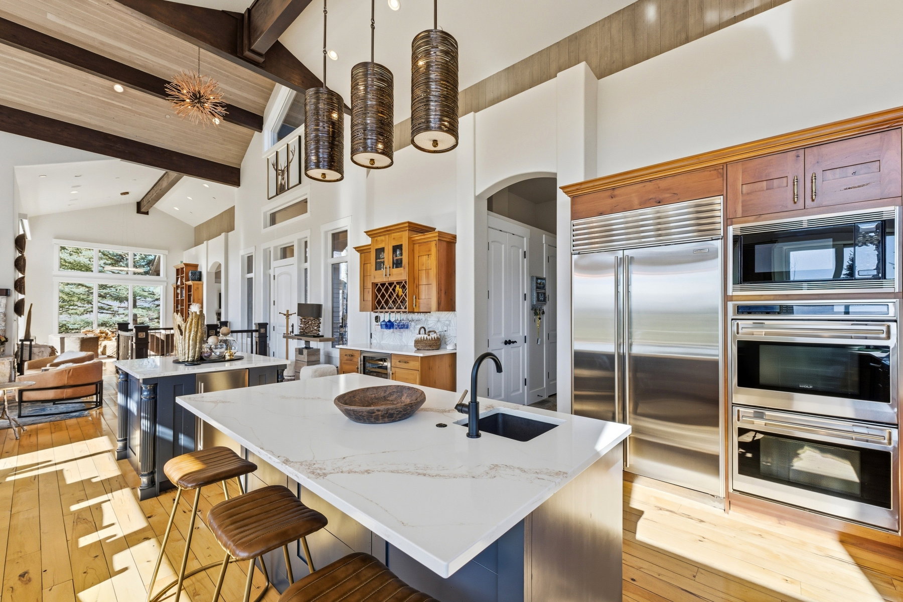 Spacious open-concept kitchen featuring two islands with stone countertops, a built-in stainless steel refrigerator, and integrated stainless steel double ovens