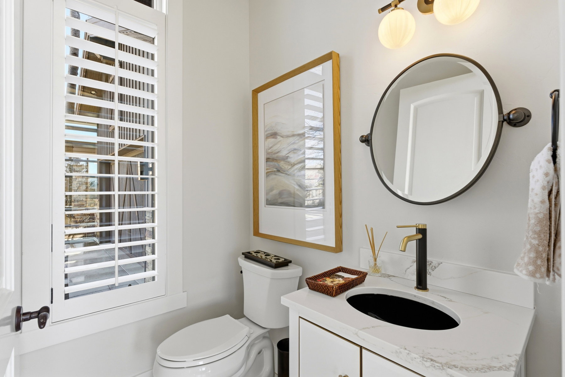 Bathroom featuring a white vanity with a stone-finish countertop, undermount sink, and a black and gold-tone faucet