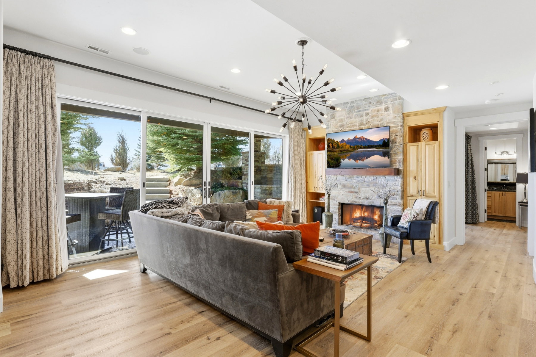 Living area featuring a stone fireplace with a wood mantle, built-in cabinetry, and wood-finish flooring