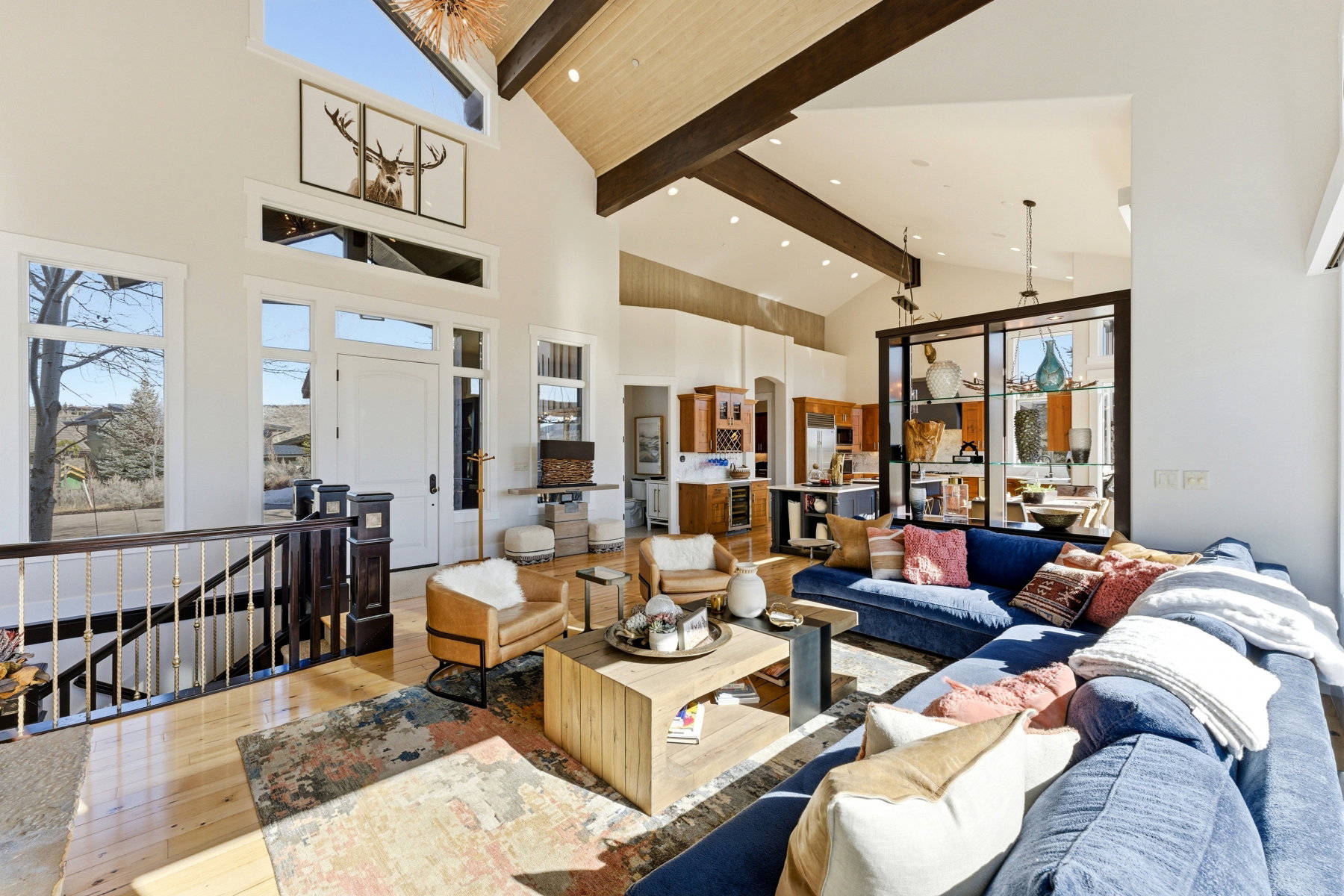 Vaulted ceiling living area featuring hardwood flooring, exposed ceiling beams, a striking two-story entry, and an open-concept layout