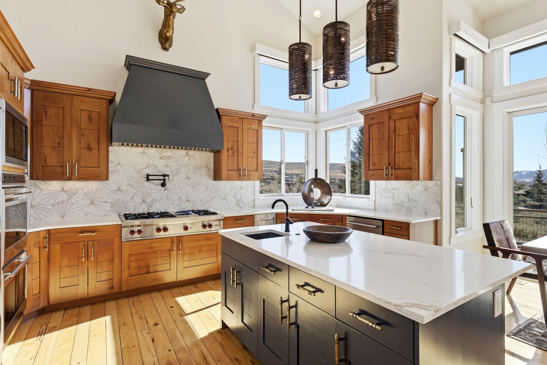 Gourmet kitchen with natural wood cabinetry, stainless steel appliances, a center island with a white countertop and dark base, and a tiled backsplash