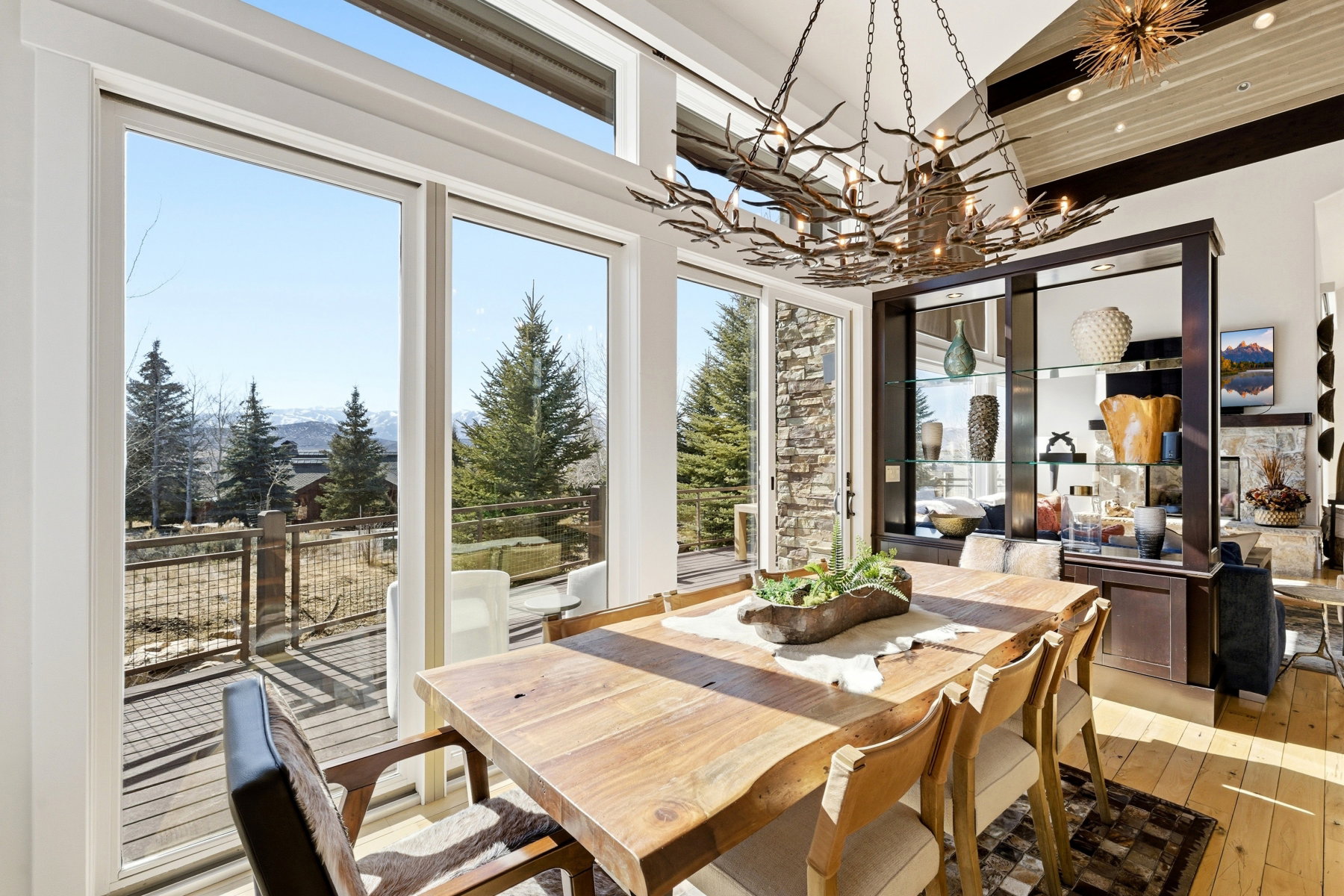 Dining area featuring full-height windows, a wood-finish dining table, and a branch-style chandelier
