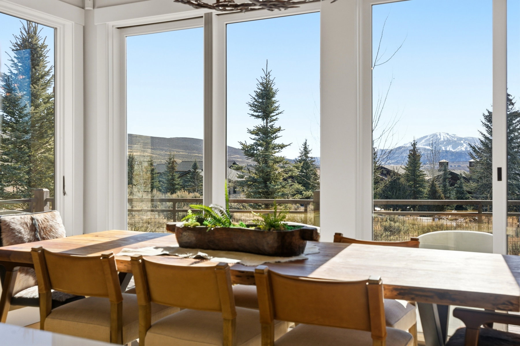 Expansive window wall with multiple panels, capturing a mountain and tree-lined landscape