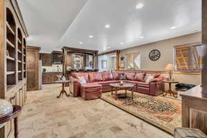 Living room featuring bar with sink, stone tile floors, and recessed lighting