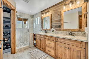 Full bathroom with a marble finish shower and double vanity