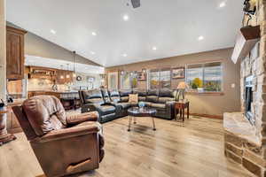 Living room with light wood-style floors, a fireplace, recessed lighting, lofted ceiling, and ceiling fan