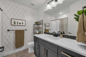 Bathroom featuring vanity, curtained shower, light wood-type flooring, and tasteful backsplash