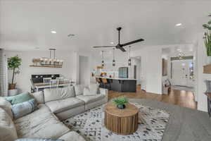 Living room with suspended lighting, a ceiling fan, and wood finished floors
