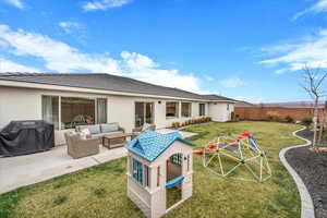 Rear view of house featuring a playground, a patio, stucco siding, and a fenced backyard