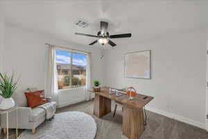 Carpeted home office featuring baseboards and a ceiling fan