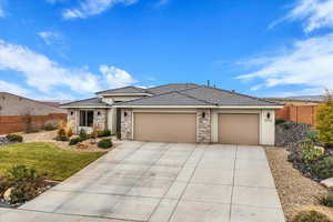 View of front of property featuring a tiled roof, stucco siding, driveway, a garage, and stone siding