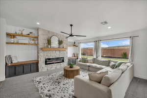 Living area with carpet floors, a fireplace, ceiling fan, and lofted ceiling