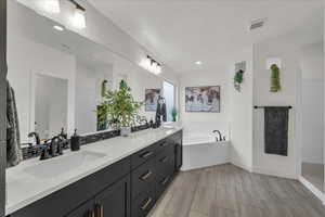 Bathroom featuring double vanity, a garden tub, vaulted ceiling, and recessed lighting