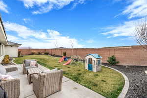 Fenced backyard featuring a playground, a patio, and outdoor seating