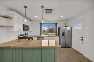 Kitchen with pendant lighting, white cabinetry, stainless steel appliances, and open shelves