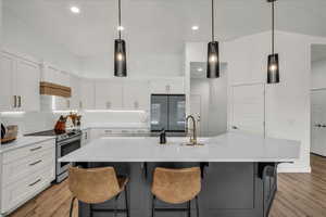 Kitchen featuring decorative light fixtures, stainless steel appliances, dual tone cabinetry, an island with sink, and tasteful backsplash