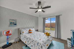 Bedroom with dark carpet, ceiling fan, and an accent wall