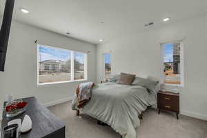 Bedroom featuring light carpet, multiple windows, and recessed lighting