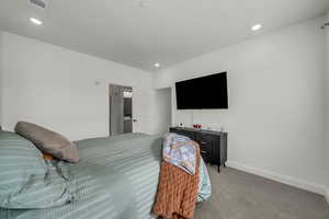 Carpeted bedroom with ensuite bath and recessed lighting