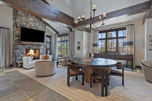Dining space with stone tile flooring, a fireplace, lofted ceiling, and suspended lighting