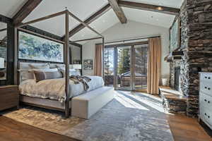 Bedroom with dark wood-style floors, access to outside, and a stone fireplace