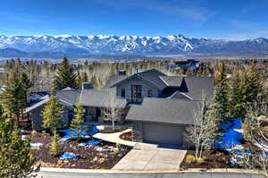 View of front facade featuring board and batten siding, stone siding, a mountain view, and concrete driveway