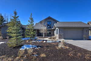 View of front of house featuring board and batten siding, concrete driveway, covered porch, and stone siding