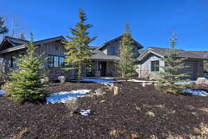 Rear view of property featuring board and batten siding, stone siding, and a patio area