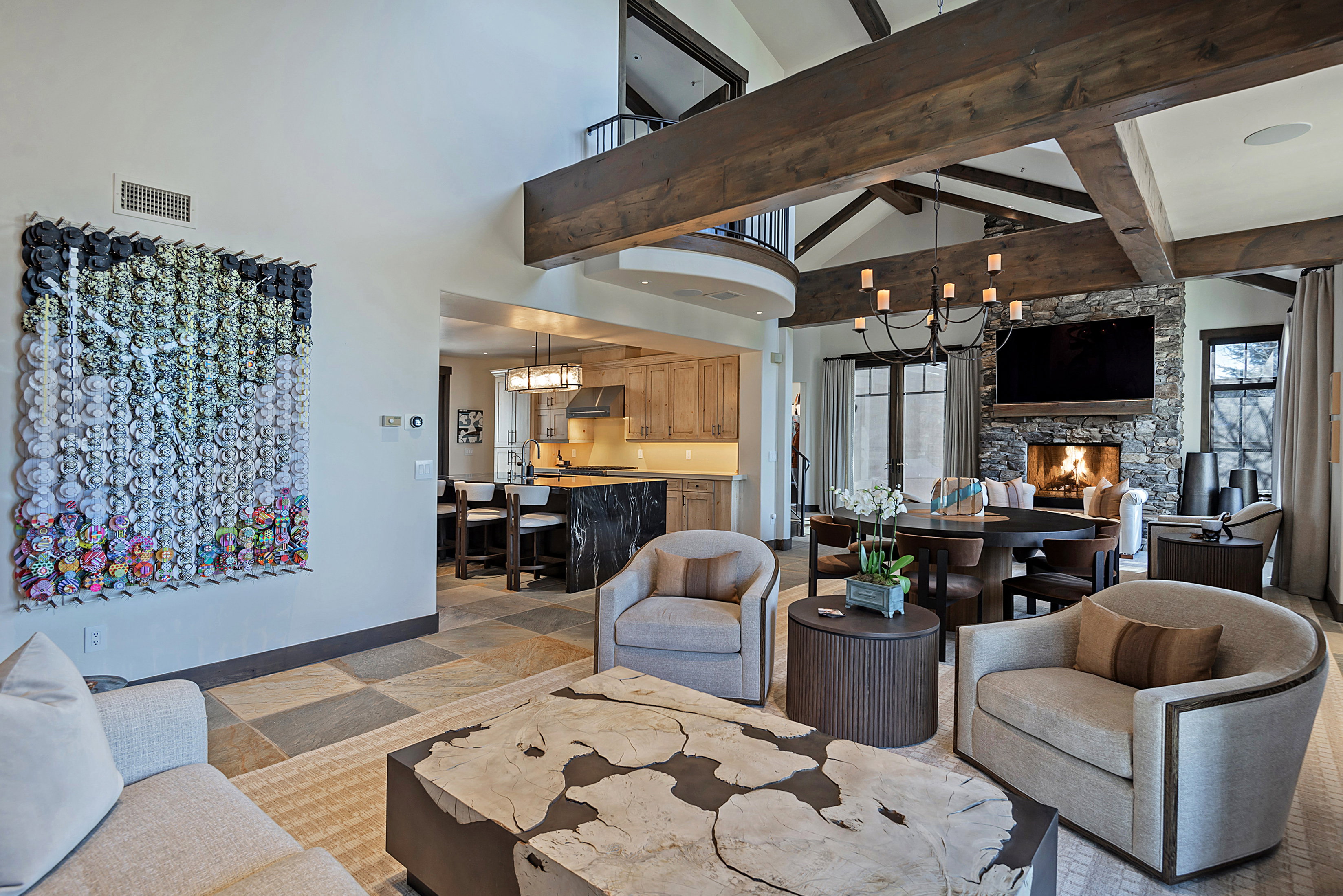 Living room featuring a fireplace, light stone finish flooring, a chandelier, and vaulted ceiling