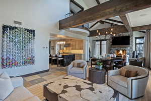 Living room featuring a fireplace, light stone finish flooring, a chandelier, and vaulted ceiling