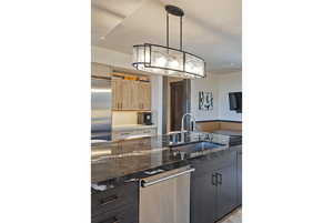 Kitchen with two tone cabinets, decorative light fixtures, dark stone countertops, and stainless steel appliances