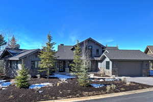 View of front of home featuring board and batten siding, stone siding, a chimney, and an attached garage