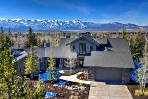 View of front facade with stone siding, a mountain view, concrete driveway, board and batten siding, and a garage