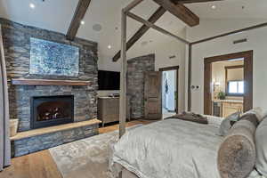 Bedroom with hardwood / wood-style floors, a fireplace, vaulted ceiling, and wine cooler
