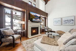 Living area featuring hardwood / wood-style flooring, a lit fireplace, a high ceiling, and healthy amount of natural light