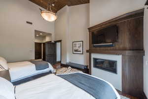 Bedroom with a high wooden ceiling, a glass covered fireplace, and wood finished floors