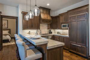 Kitchen with a breakfast bar, pendant lighting, built in appliances, and backsplash
