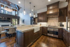 Kitchen with a peninsula, a breakfast bar area, dark wood finish cabinets, open floor plan, and pendant lighting