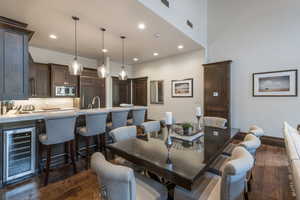 Dining area with dark wood finished floors, wine cooler, and recessed lighting