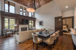 Dining area with dark wood-type flooring, a fireplace, recessed lighting, healthy amount of natural light, and vaulted ceiling