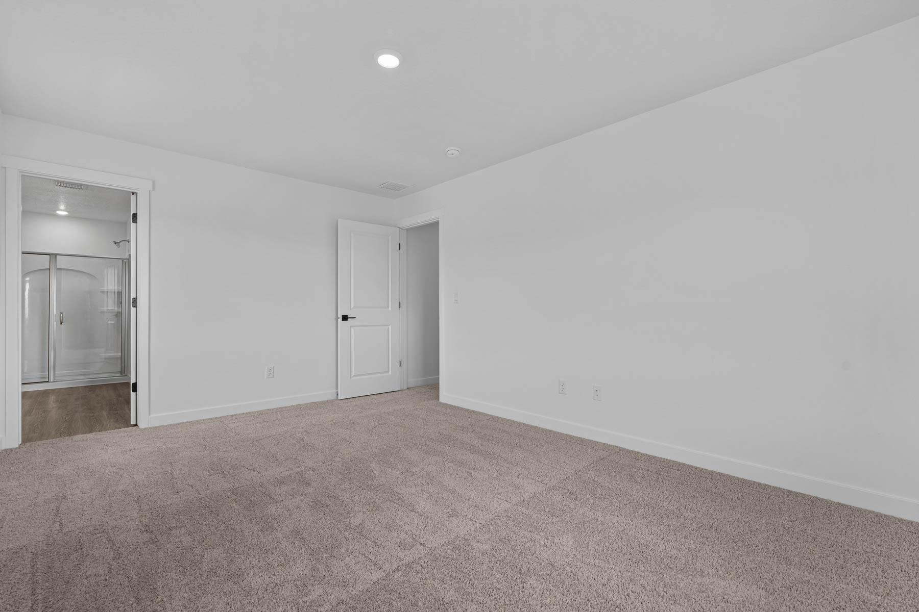 Neutral-toned wall-to-wall carpeting in a spacious room featuring a recessed light fixture