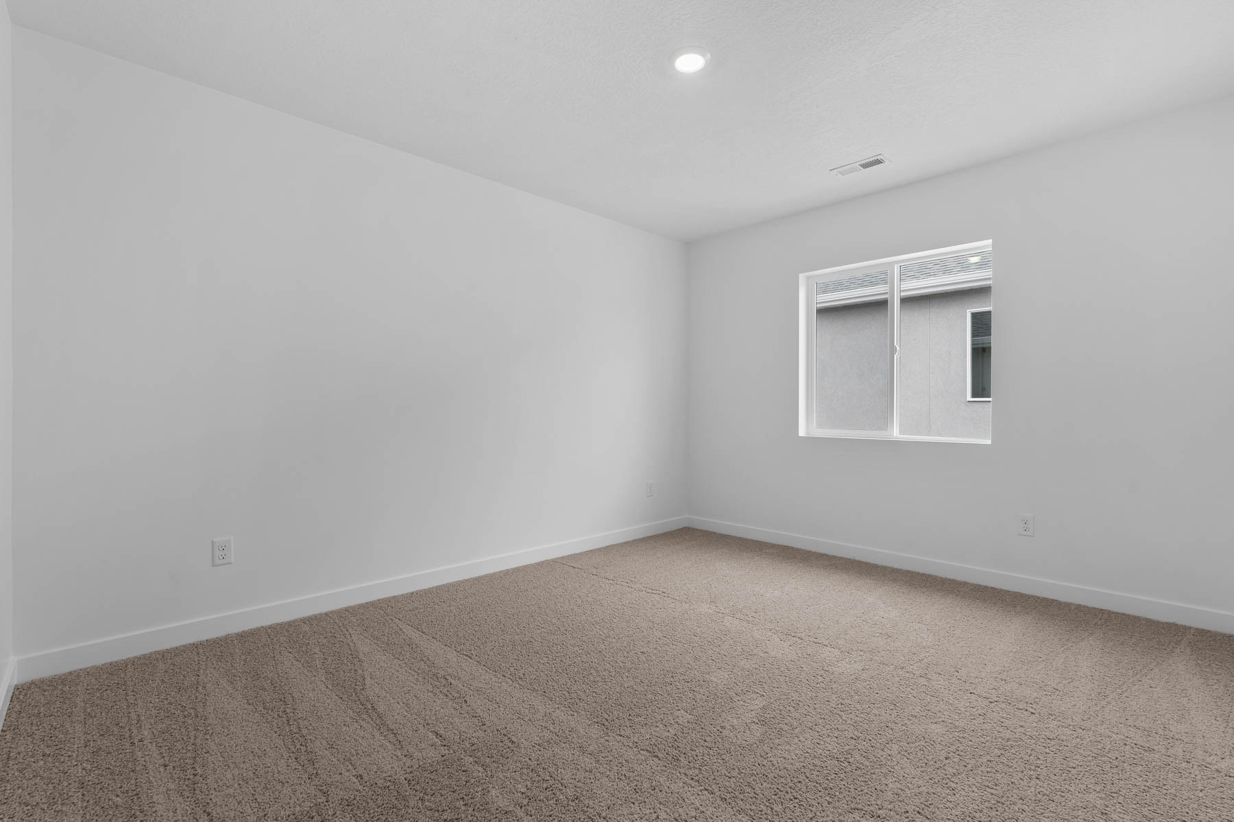 Neutral tone carpeting with white baseboards and walls