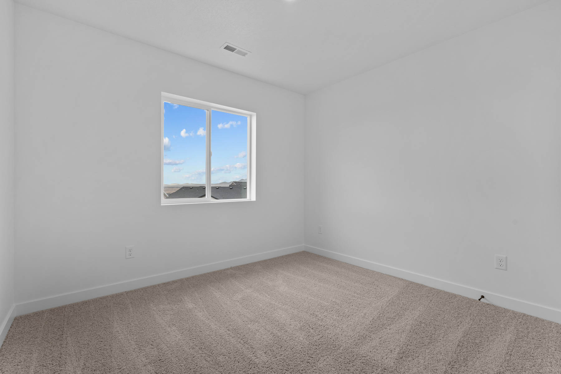 White interior walls with a single window featuring a white frame and blue sky scenery