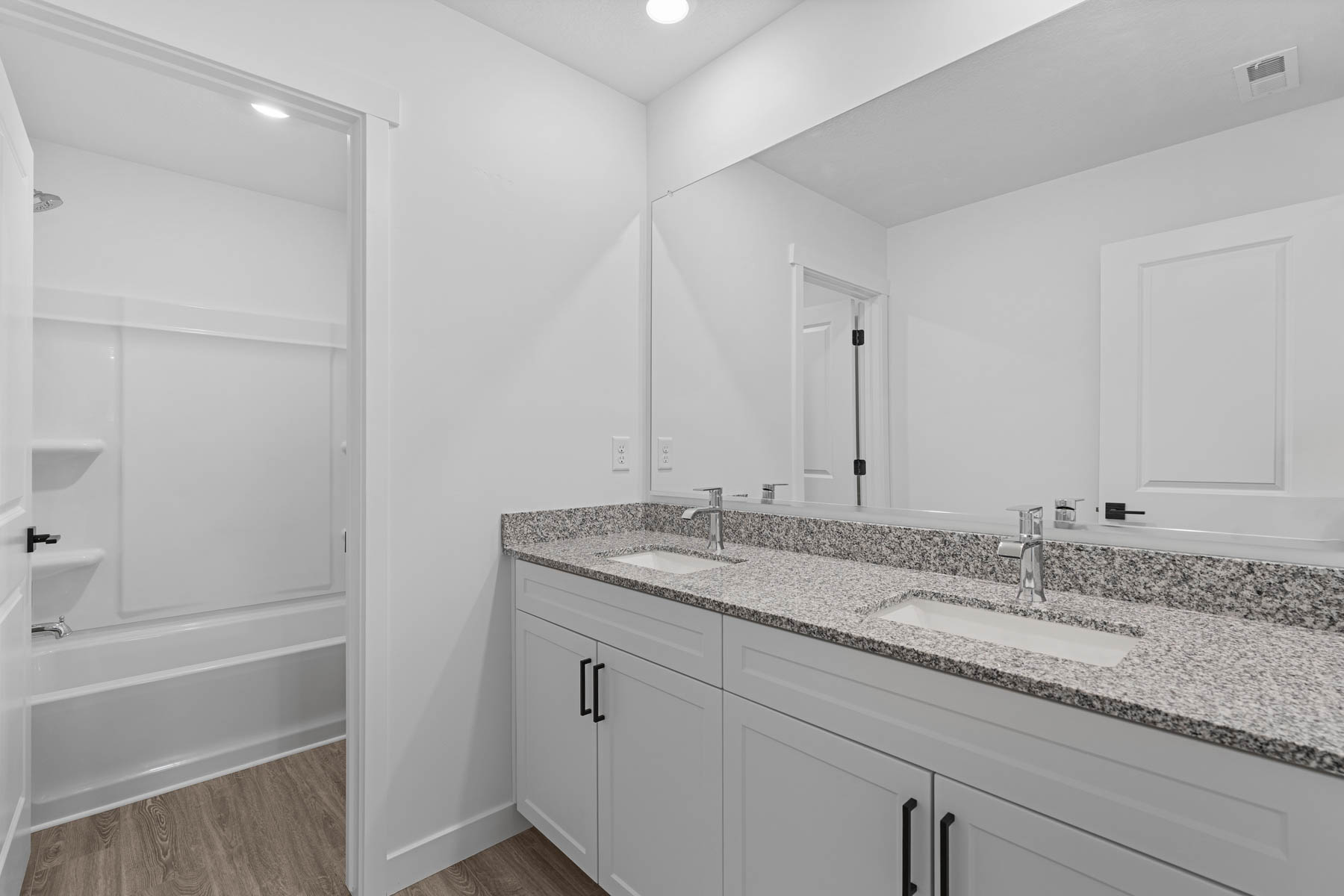 Double vanity featuring granite-finish countertops, undermount sinks, and chrome faucets