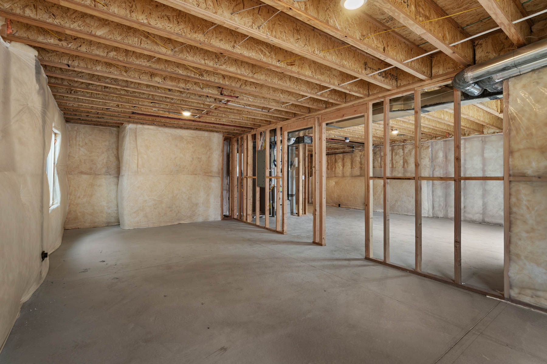 Spacious unfinished basement featuring exposed wood joists and framing, concrete flooring, and recessed lighting