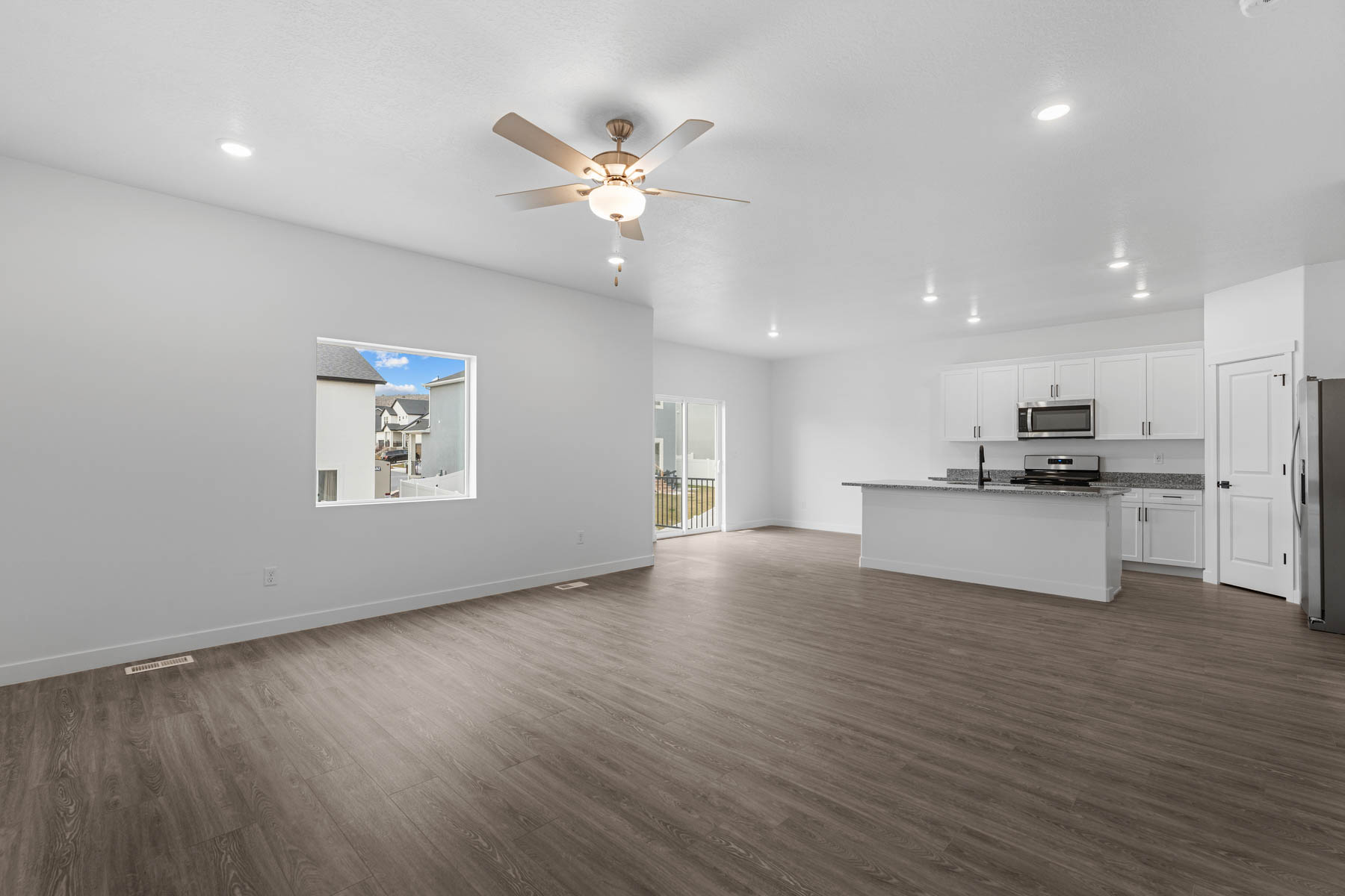 Expansive open-concept living space featuring wood-finish flooring, recessed lighting, and a ceiling fan